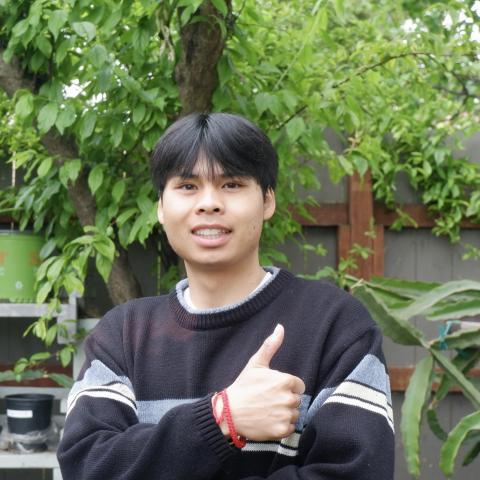 Brandon is standing in the middle of the frame, facing the camera and smiling. 